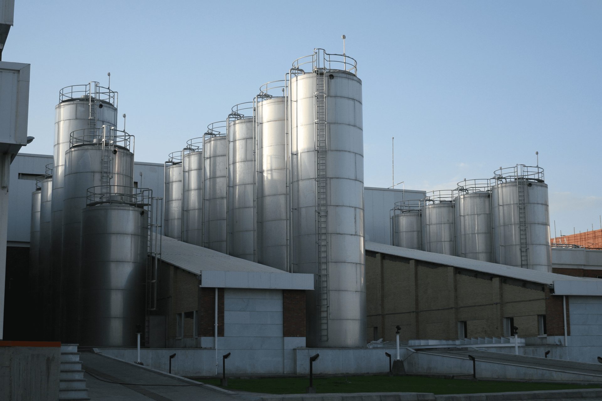 Large stainless steel dairy milk silos on plinths - external and structural integrity inspection